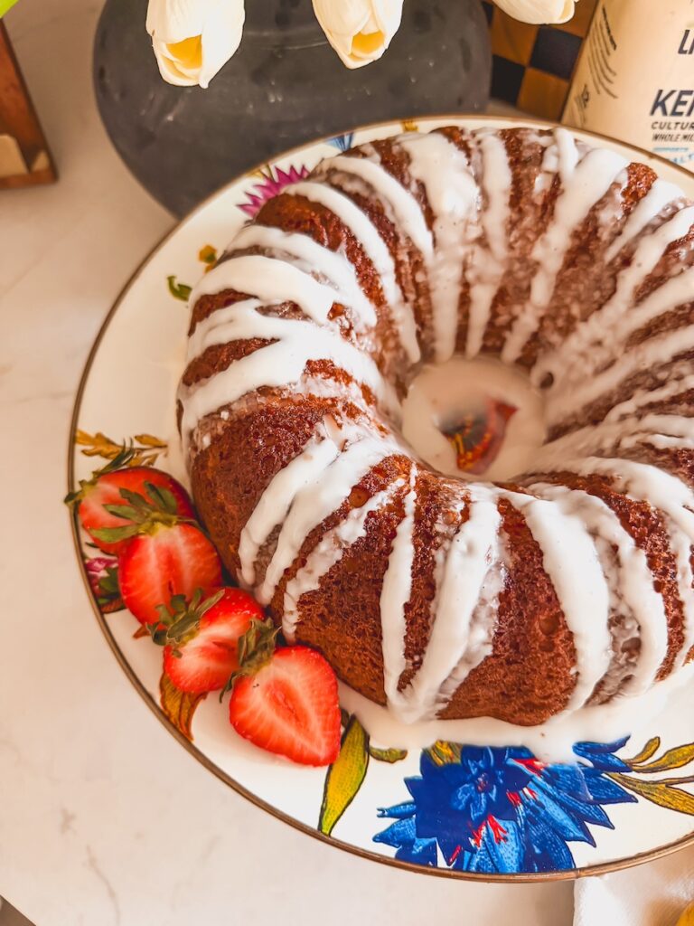 whole lemon bundt cake on plate with strawberries next to it