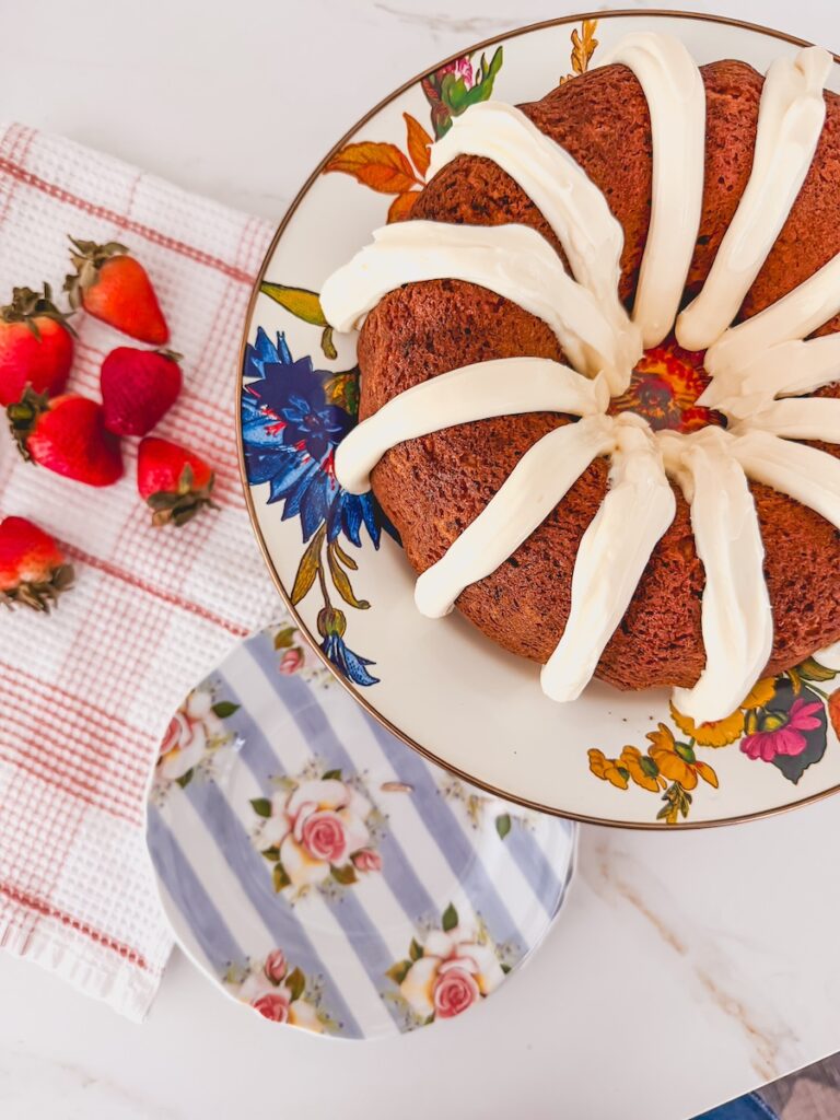 birds eye view of whole, unsliced strawberry bundt cake with strawberries and flower plate in background