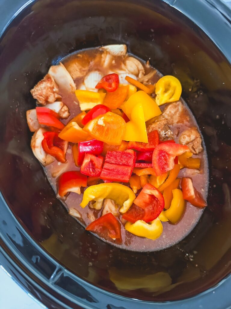 bell peppers added to slow cooker with chicken and sauce