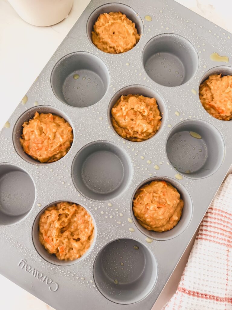 Carrot banana muffin batter is scooped into the muffin tin.