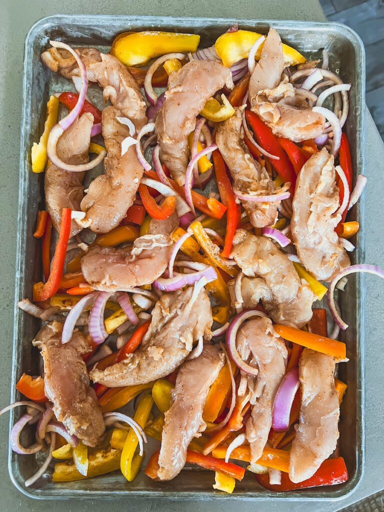 uncooked sheet pan chicken fajita ingredients on sheet pan