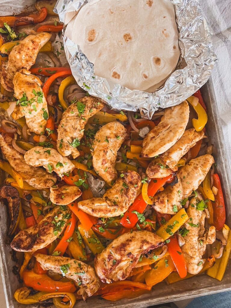 wider shot of sheet pan chicken fajitas with tortillas in foil