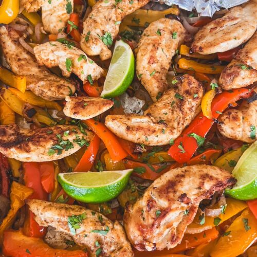 close up shot of sheet pan chicken fajitas and tortillas in corner