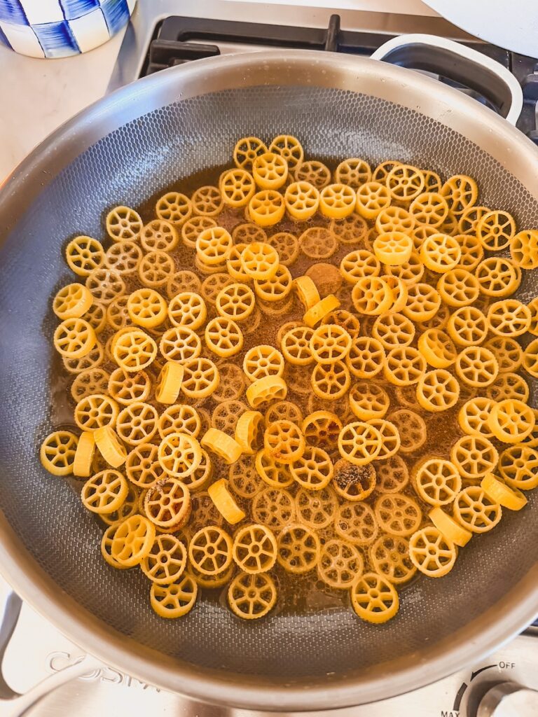 adding uncooked pasta to melted butter and olive oil in pan