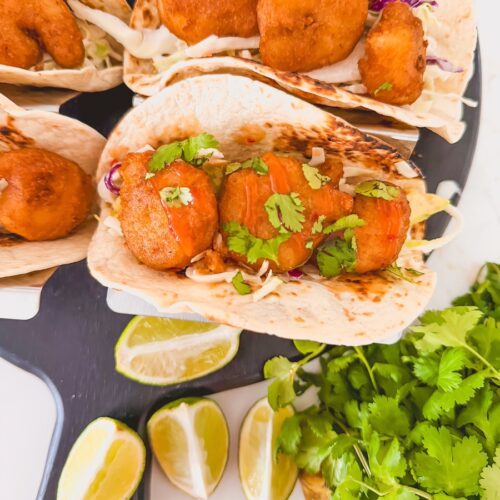 close up of beer battered shrimp taco with lime and cilantro