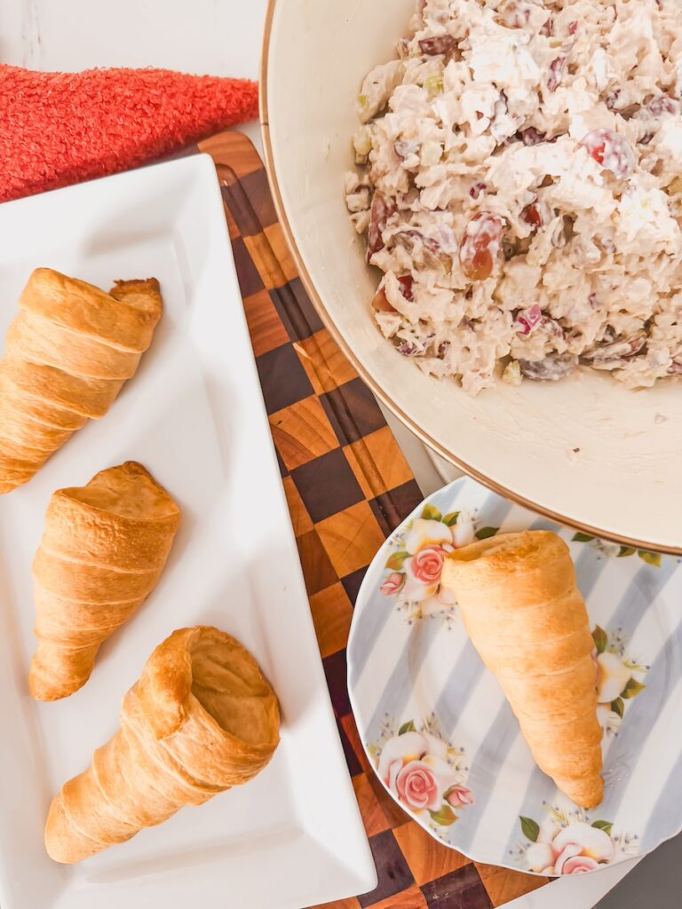crescent dough shaped like carrots with a bowl of chicken salad