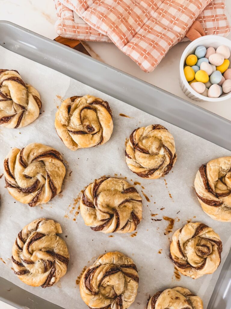pastry nests on baking sheet with bowl of chocolate eggs