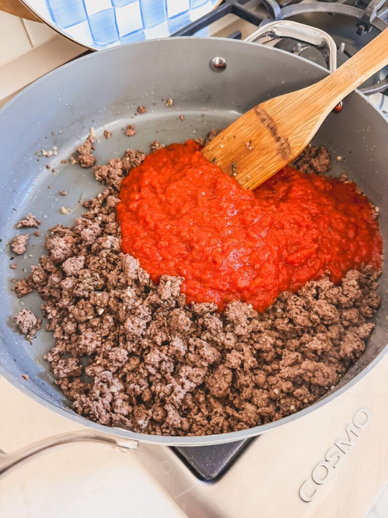 browned ground beef in pan with tomato sauce