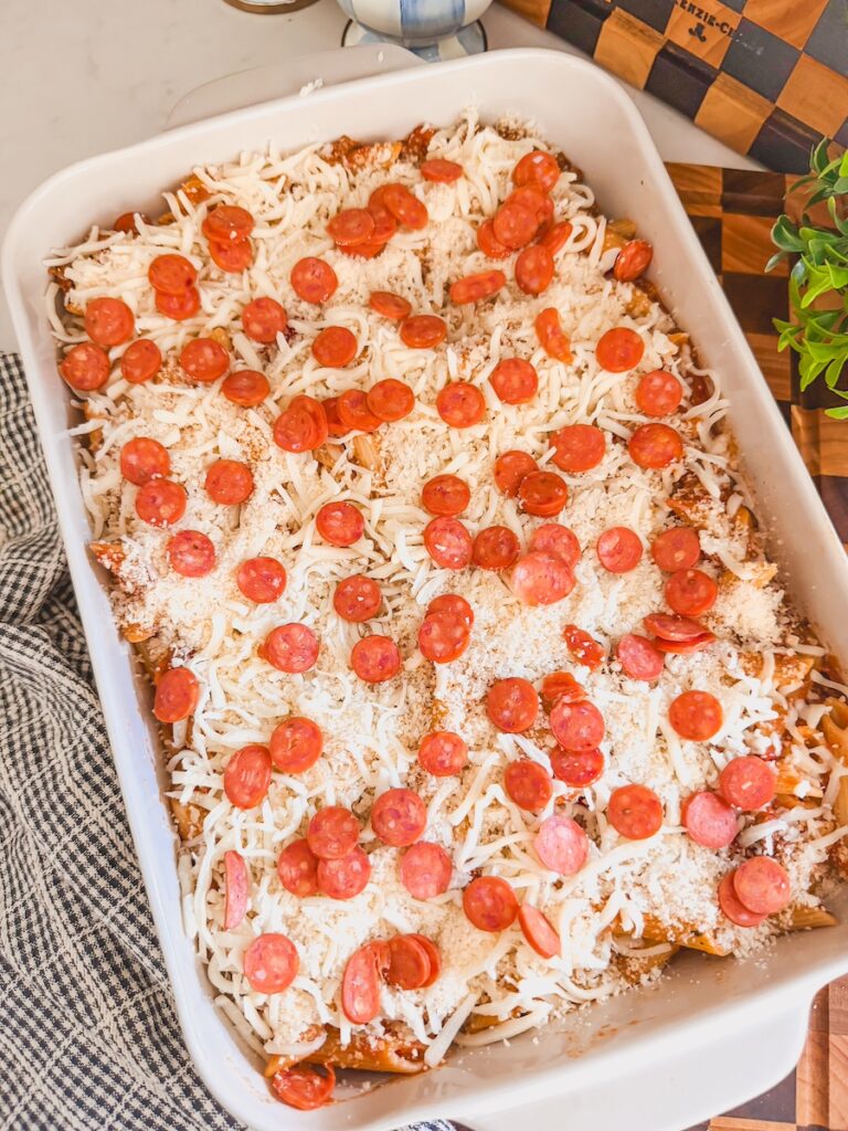 pizza casserole topped with cheese and sliced pepperoni ready to be baked