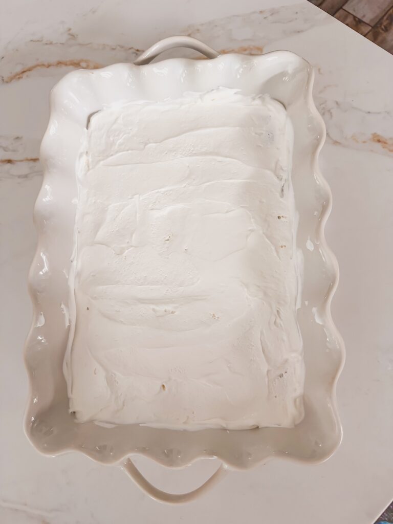 layer of whipped topping added to ice cream sandwiches in baking dish