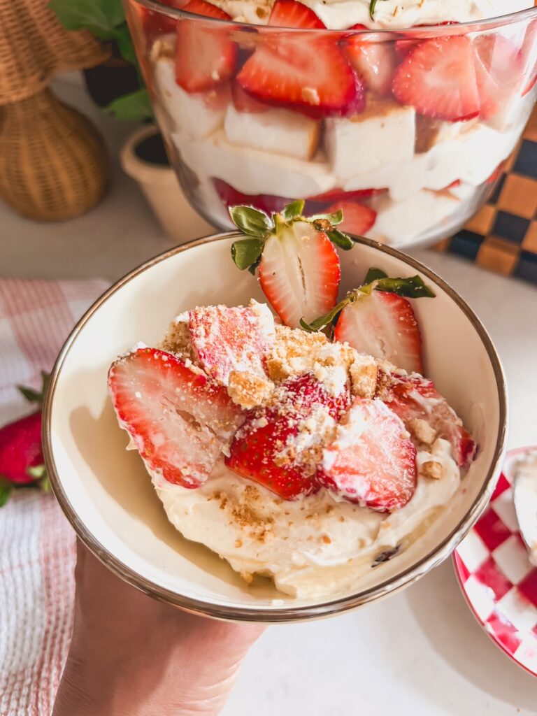 strawberry shortcake trifle serving in bowl with assembled trifle in background