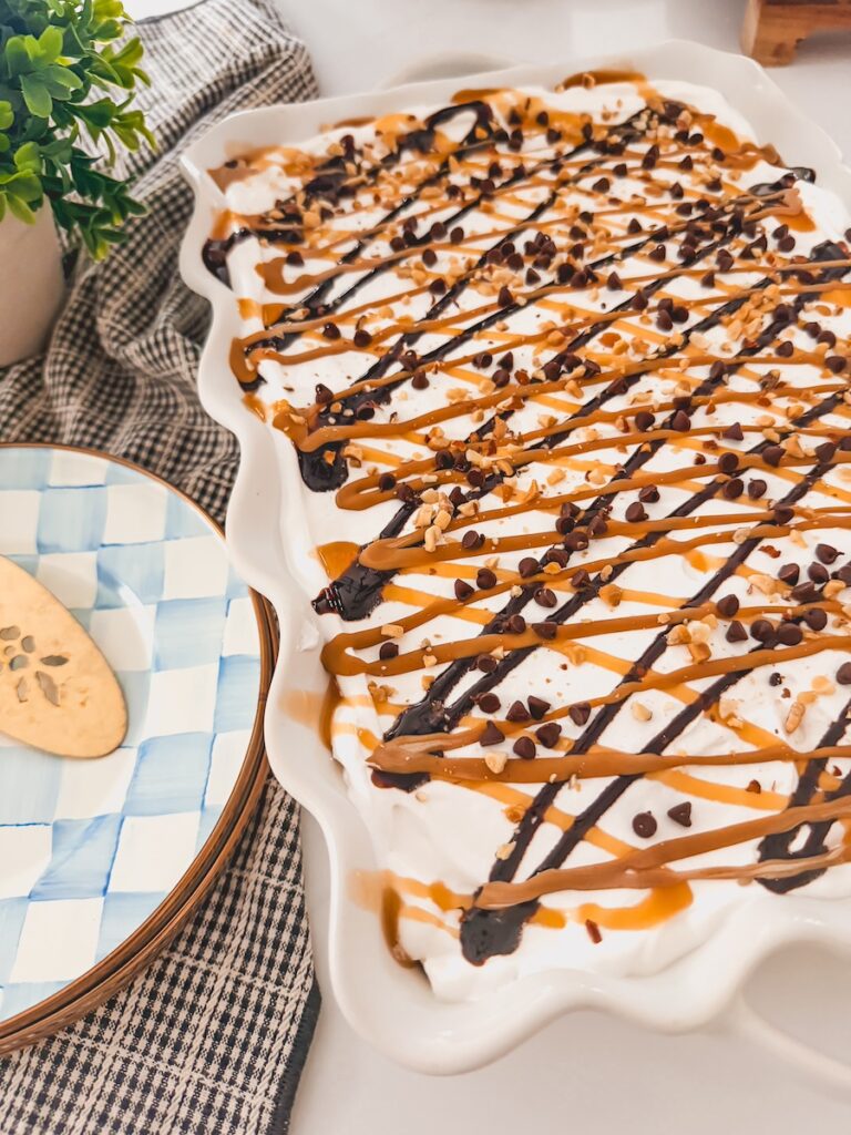 finished ice cream sandwich cake in baking dish next to plates, a serving utensil and dish towel