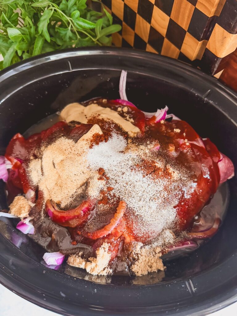 raw pork, red onions, brown sugar, spices, and bbq sauce in slow cooker