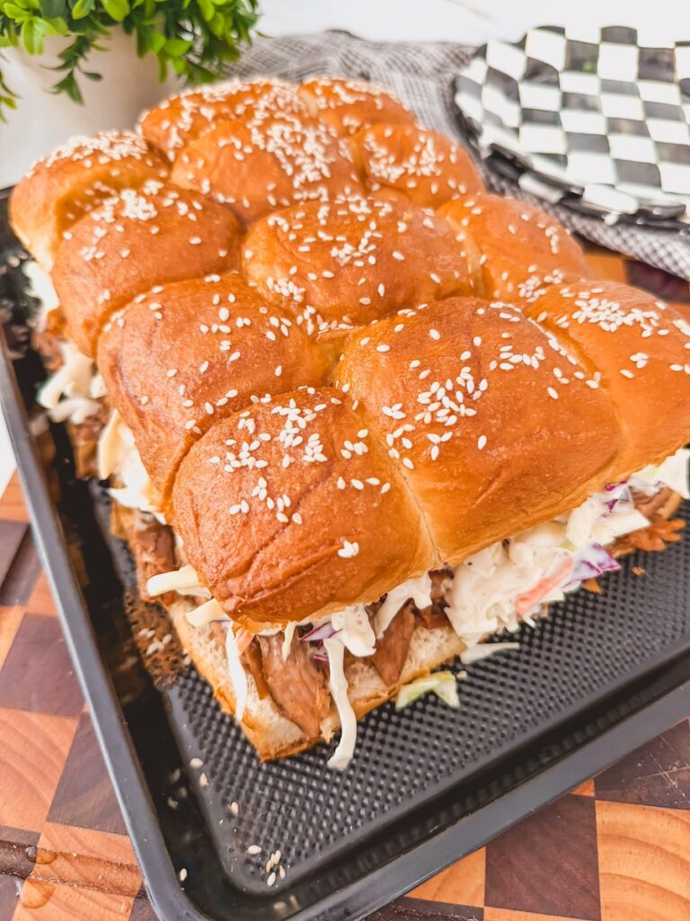 Side, overhead view of assembled pulled pork sliders. plates in background.