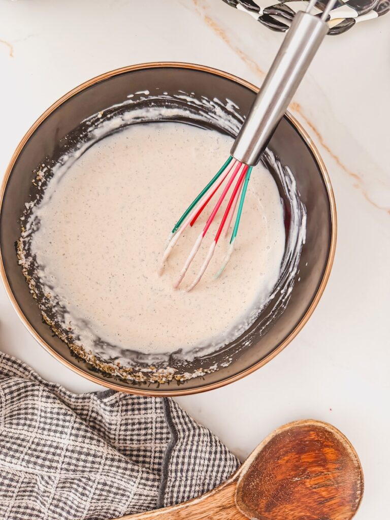 mixing Italian grinder chicken salad with creamy dressing in a large bowl