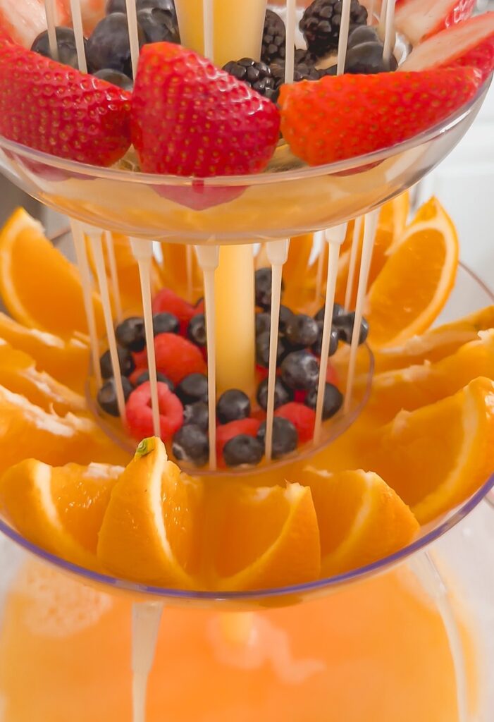 close up of mimosa tower pouring onto fresh oranges