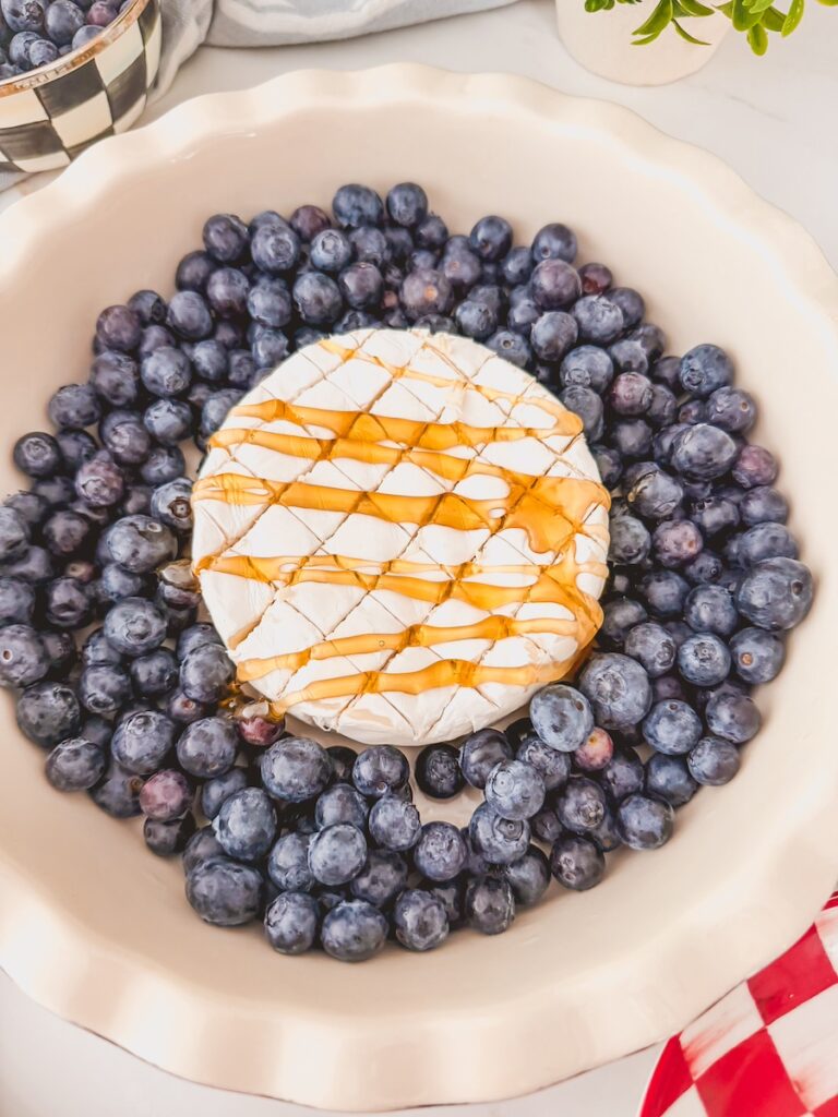 honey drizzled on top of scored baked brie with blueberries