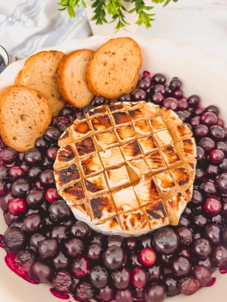 close up blueberry baked brie with baguette slices out of oven