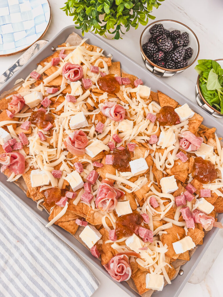 fig jam, prosciutto, and salami scattered over chips before baking