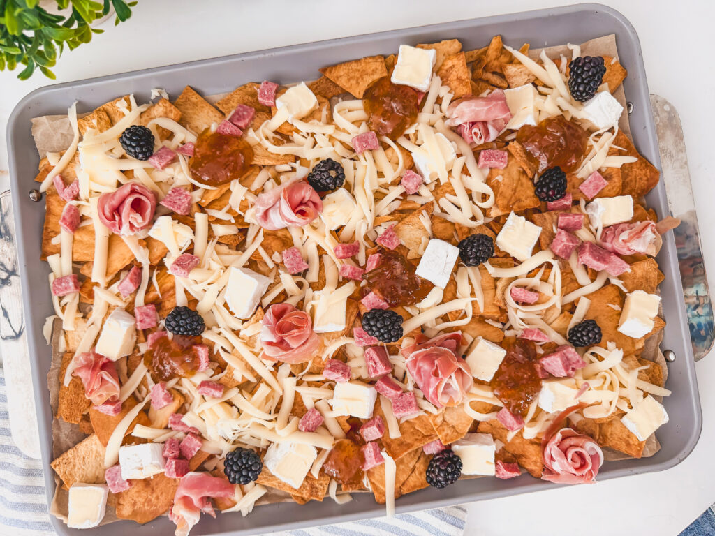 Brie, mozzarella, fig jam, blackberries, prosciutto, and salami scattered over chips before baking