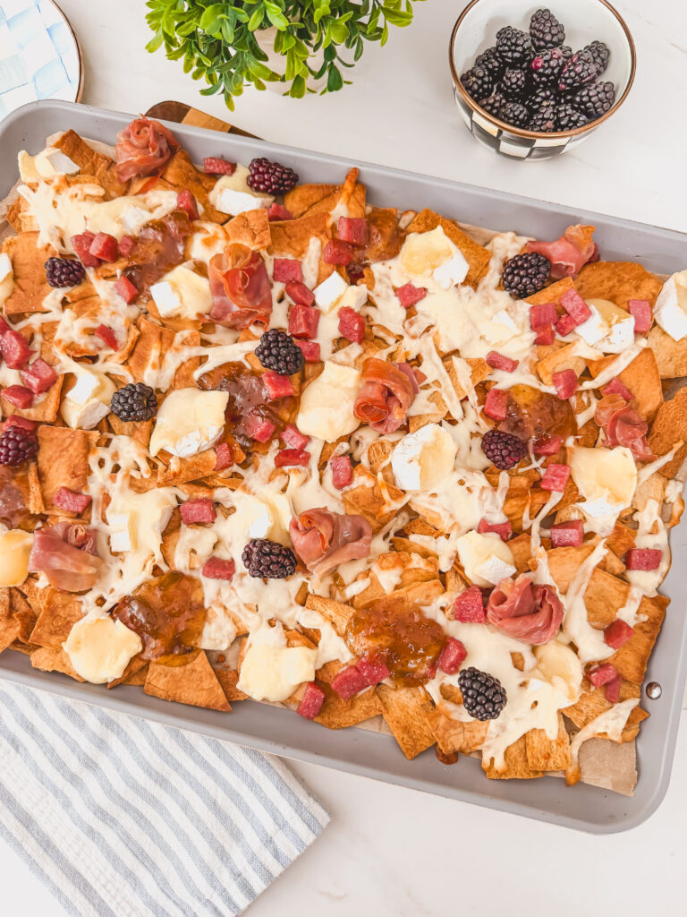 Baked charcuterie chips with melted brie and mozzarella and slightly crisped meats