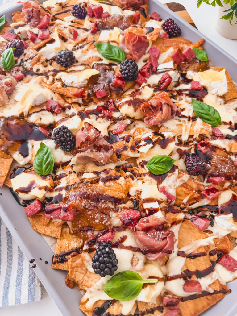 Baked charcuterie chips with brie, mozzarella, blackberries, and fig jam on a serving tray
