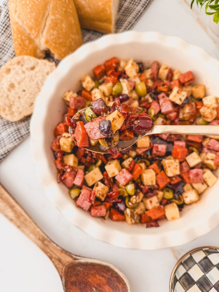 spoon full of charcuterie dip with salami, pepperoni, cheese, olives. sun dried tomatoes
