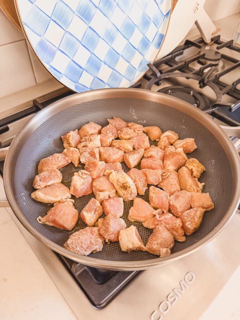 A skillet with chicken cube searing.
