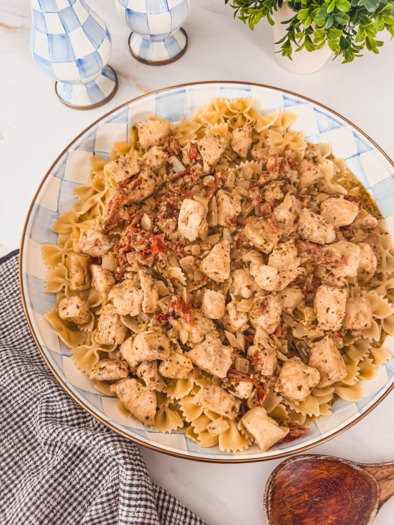 A blue and white checkered plate with chicken pesto pasta.