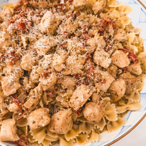 Close up image of chicken pesto pasta in a blue and white checkered bowl.