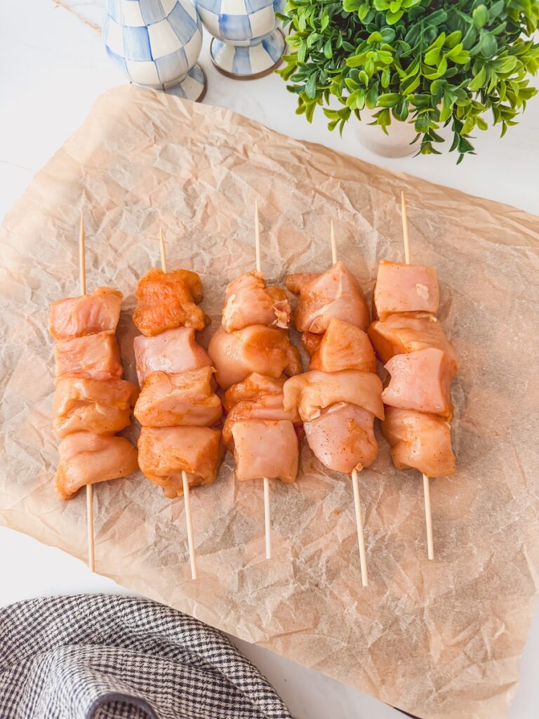 Chicken skewers threaded onto a stick tossed in spices.