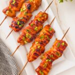Overhead image of bbq chicken kebabs on a white plate.