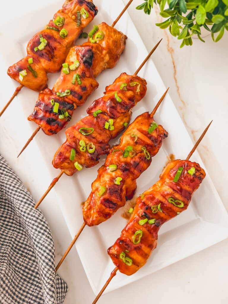 Overhead image of bbq chicken kebabs on a white plate.