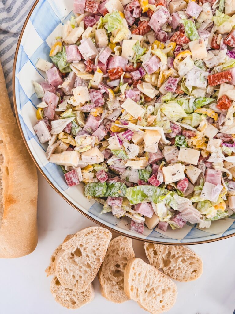 bowl of italian hoagie dip with lettuce, deli meats. deli cheeses, red onion, banana peppers, and a creamy dressing
