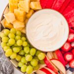 fruit platter with creamy dip along side grapes, apples, pineapple, watermelon, strawberries