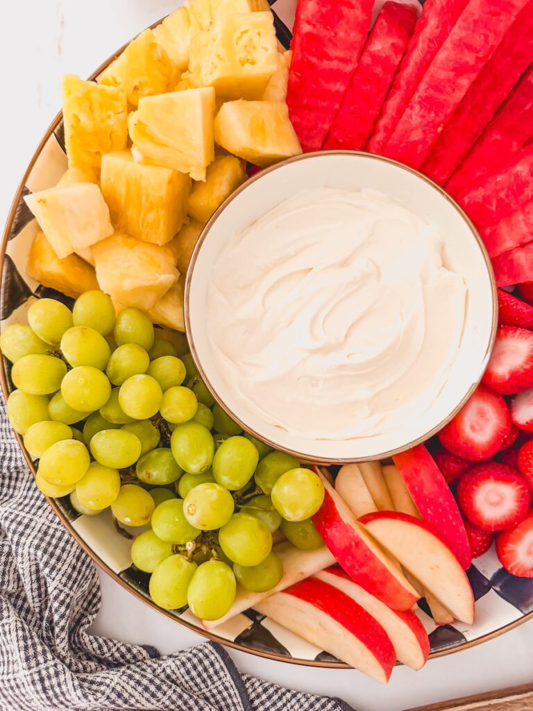 fruit platter with creamy dip along side grapes, apples, pineapple, watermelon, strawberries