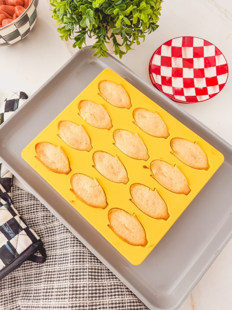 baked corn dogs in mold on sheet pan. red checked plate to the side.