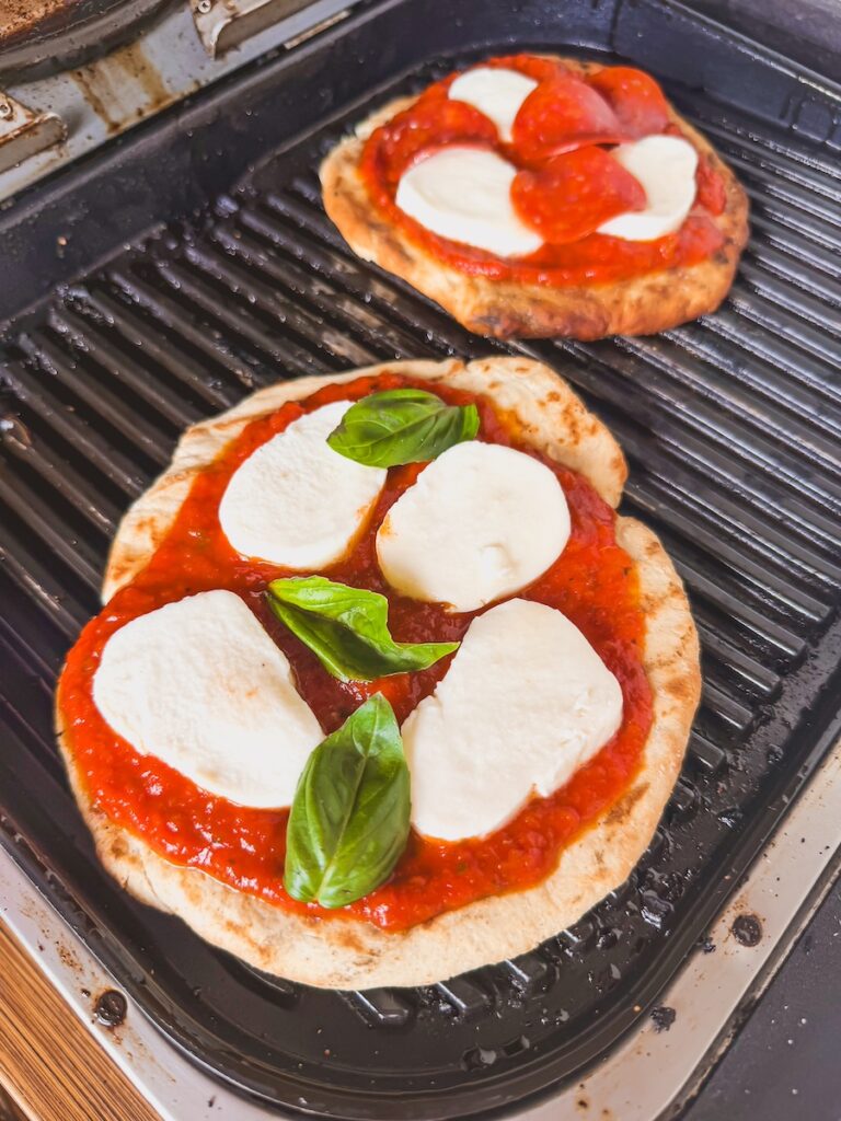 Two pizzas are grilling.