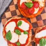 Overhead image of grilled pizzas on a checkered cutting board.