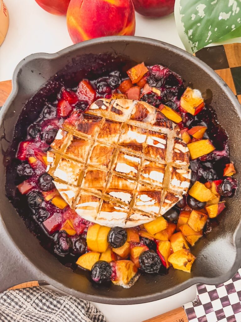grilled brie in a skillet with peaches and blueberries