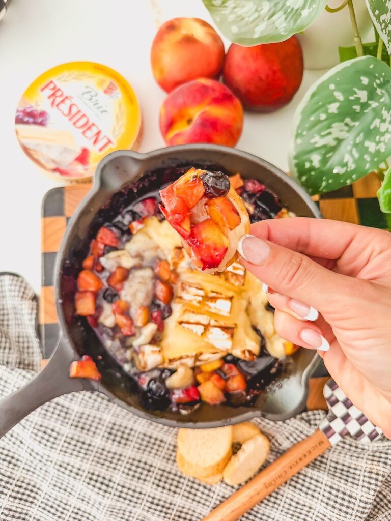 scoop of blueberry and peaches baked brie on a toasted baguette