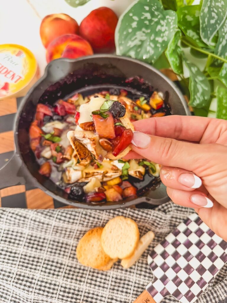 grilled peached and blueberry baked brie served on a cracker