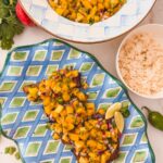 mango peach salsa on salmon plated next to bowl of rice