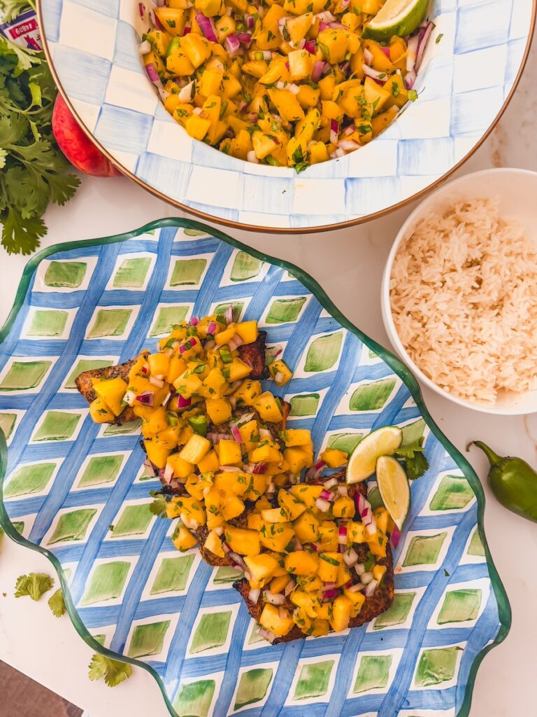 mango peach salsa on salmon plated next to bowl of rice