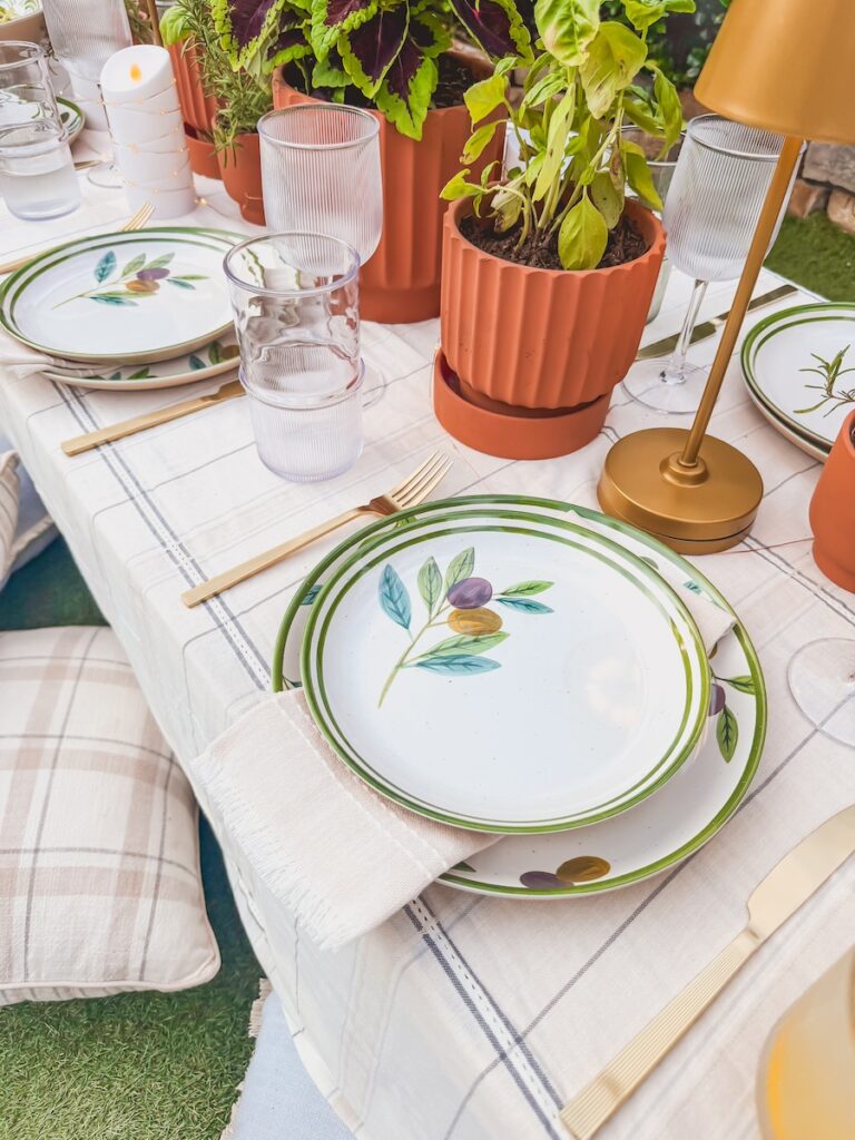 place setting close up with plates, napkins, lamp and herb centerpiece