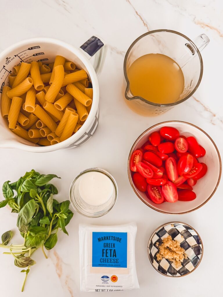 flatlay of pasta, chicken stock, basil, cream, tomatoes , garlic and feta