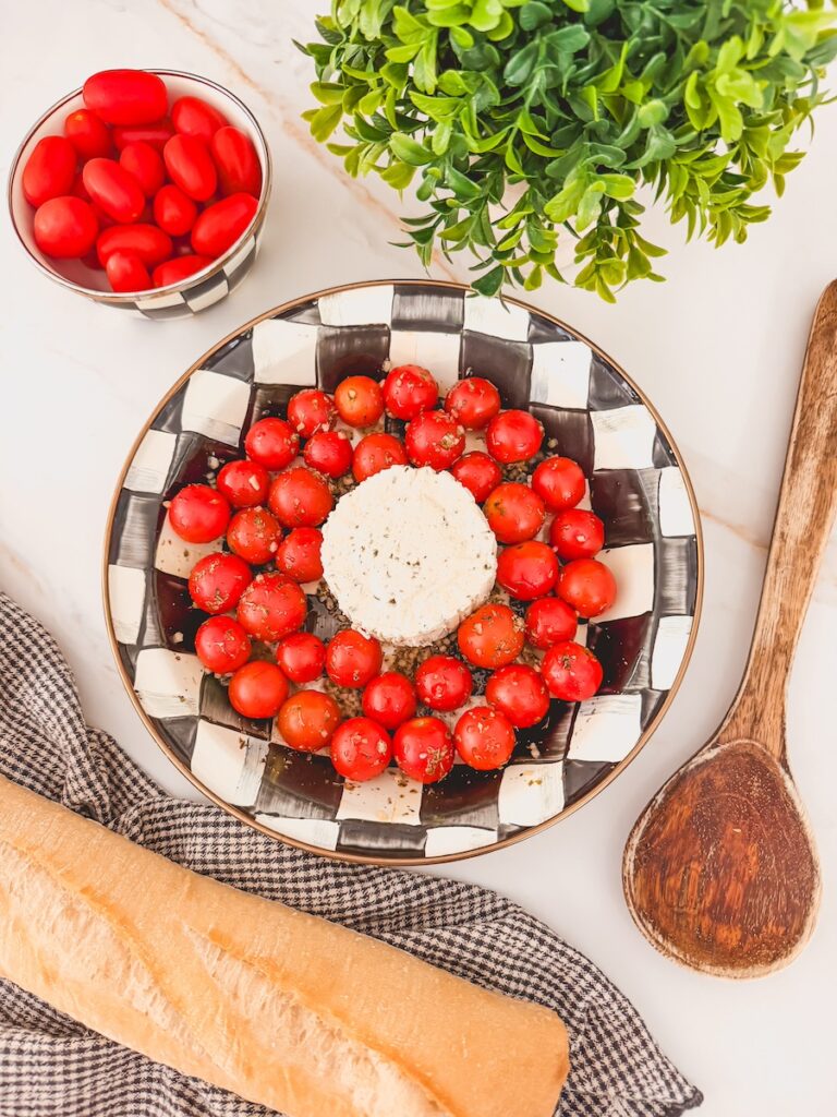 boursin placed in the middle of cherry tomatoes in baking dish