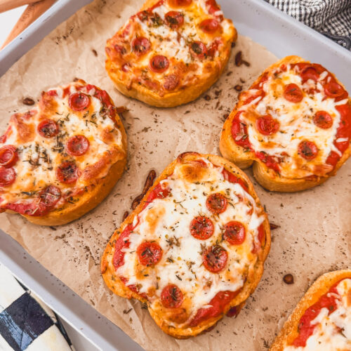 close up of baked pizza toasts on sheet tray
