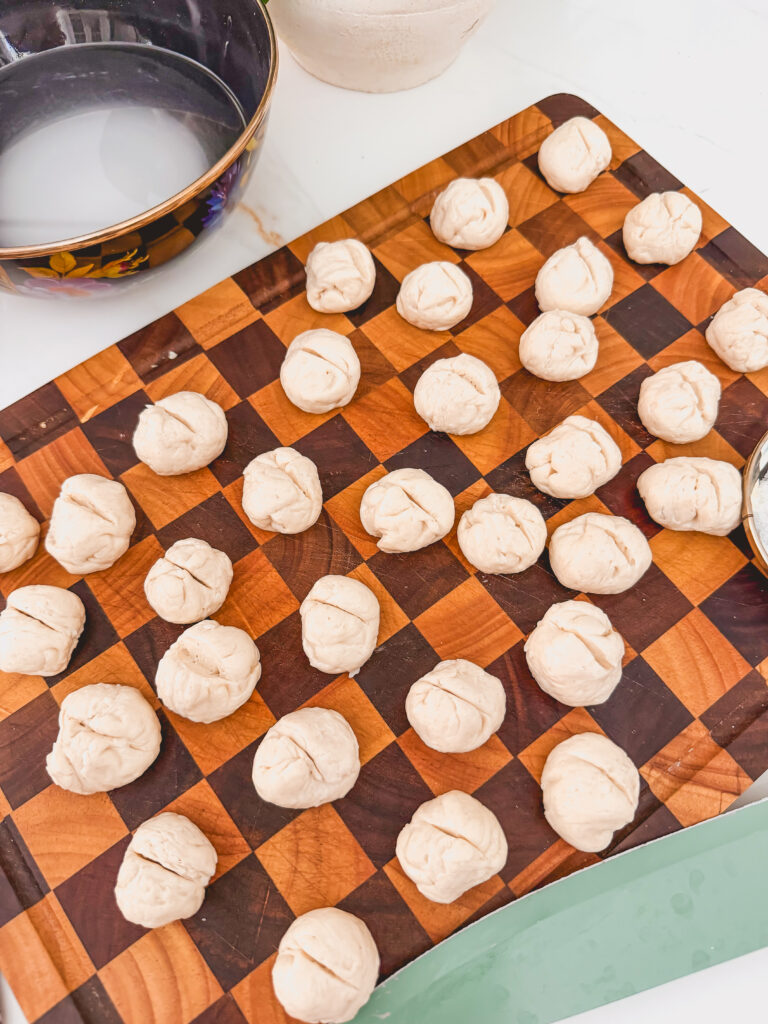 cutting board with biscuit dough balls with slits