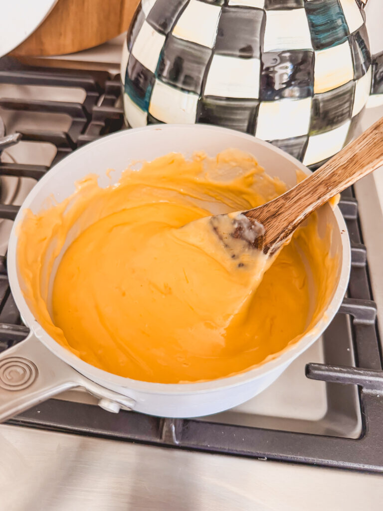 cheese sauce in pot on stove with wooden spoon